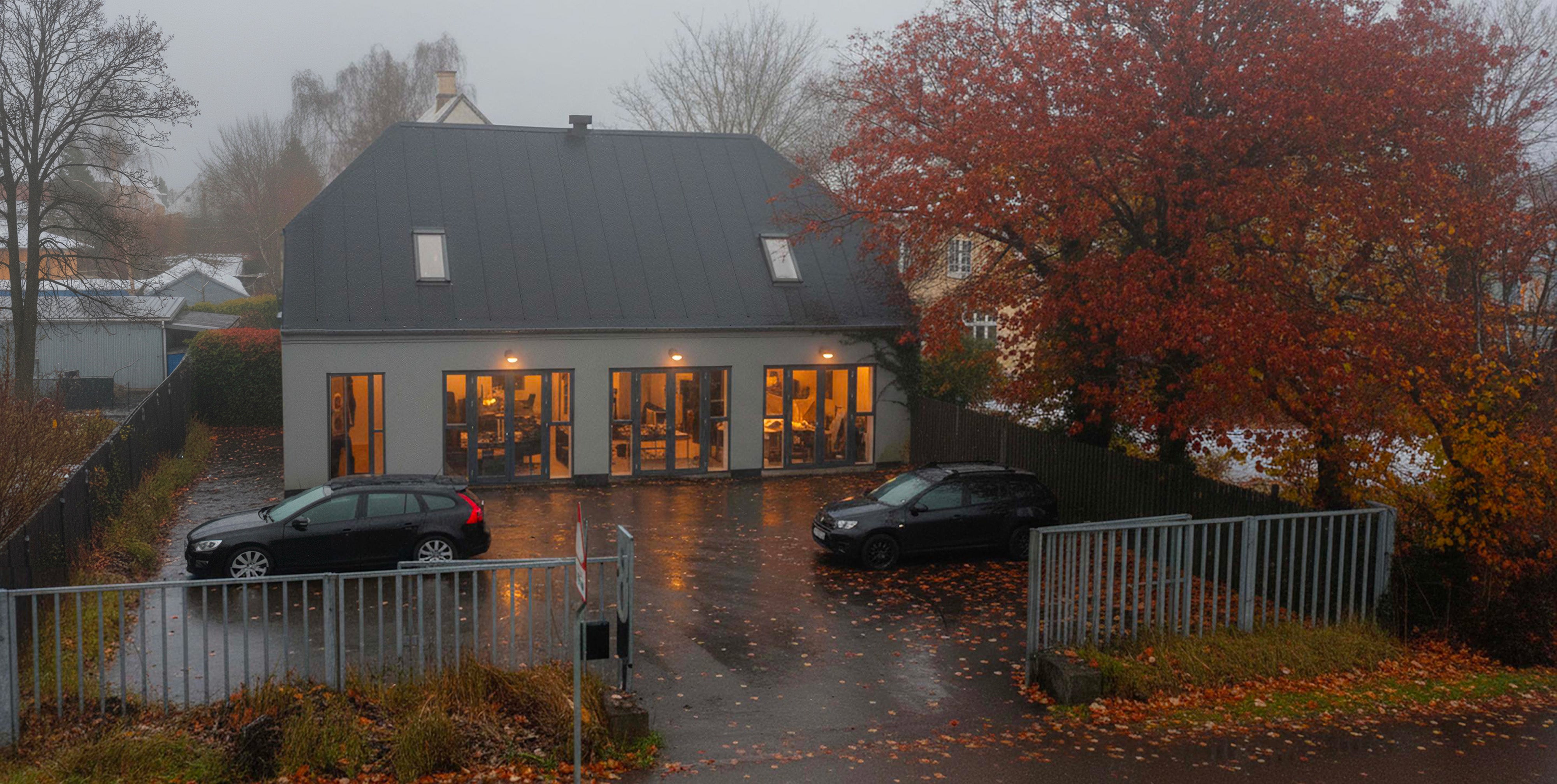 Millibar house with large windows on a rainy day, surrounded by trees with autumn foliage.