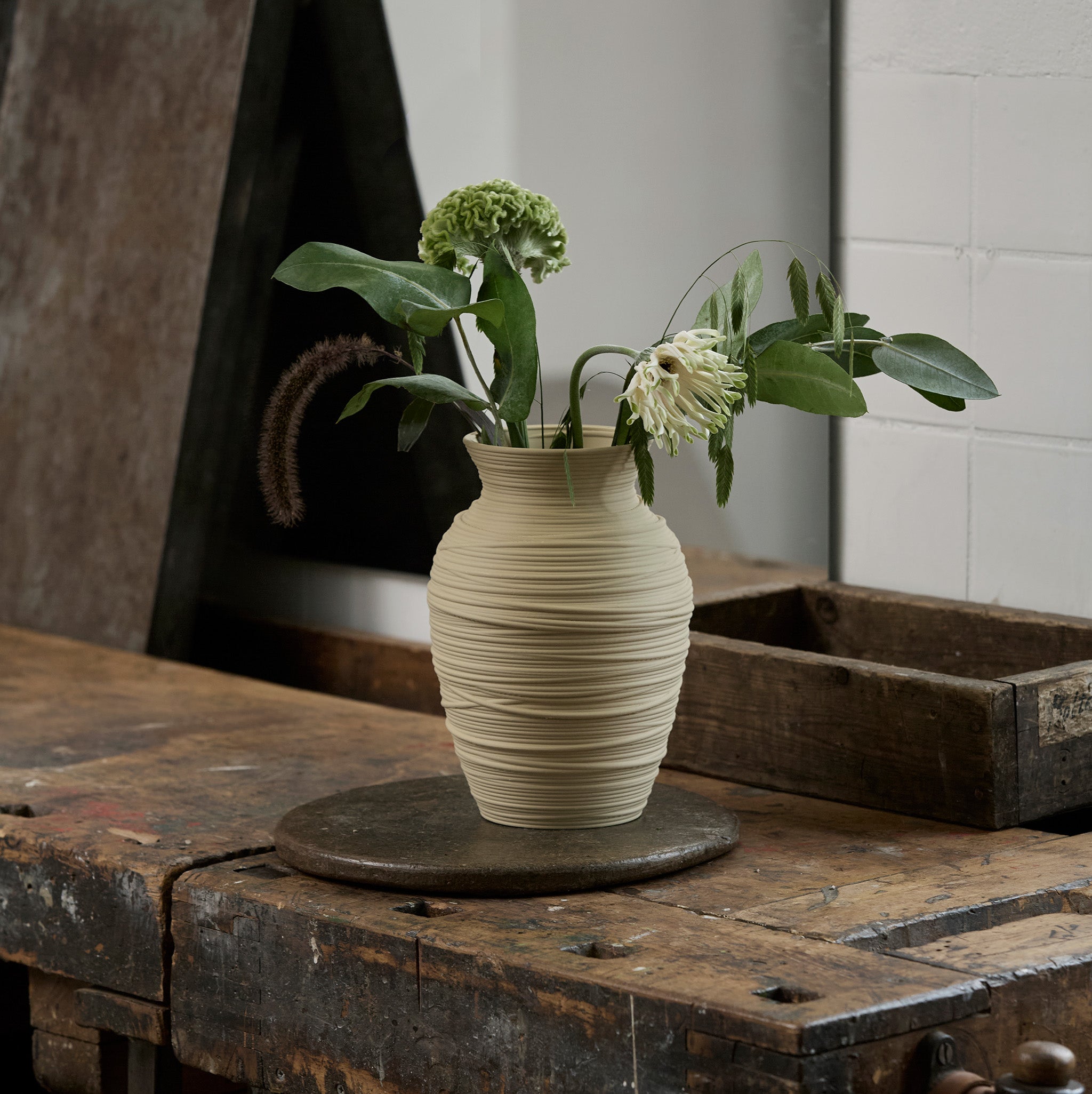 Beige textured vase with flowers on a rustic wooden table