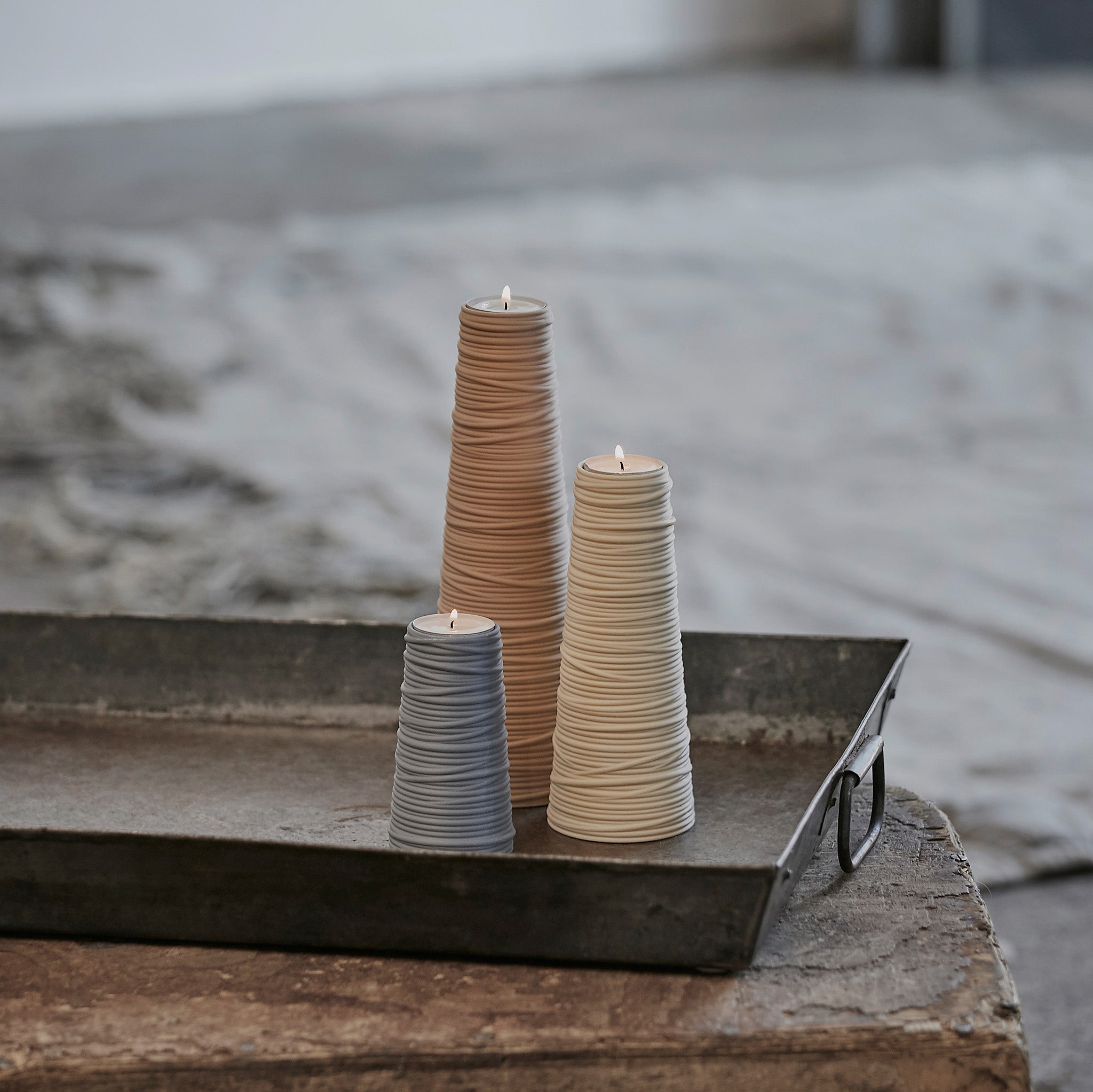 Three lid tea light holders on a metal tray with a neutral background