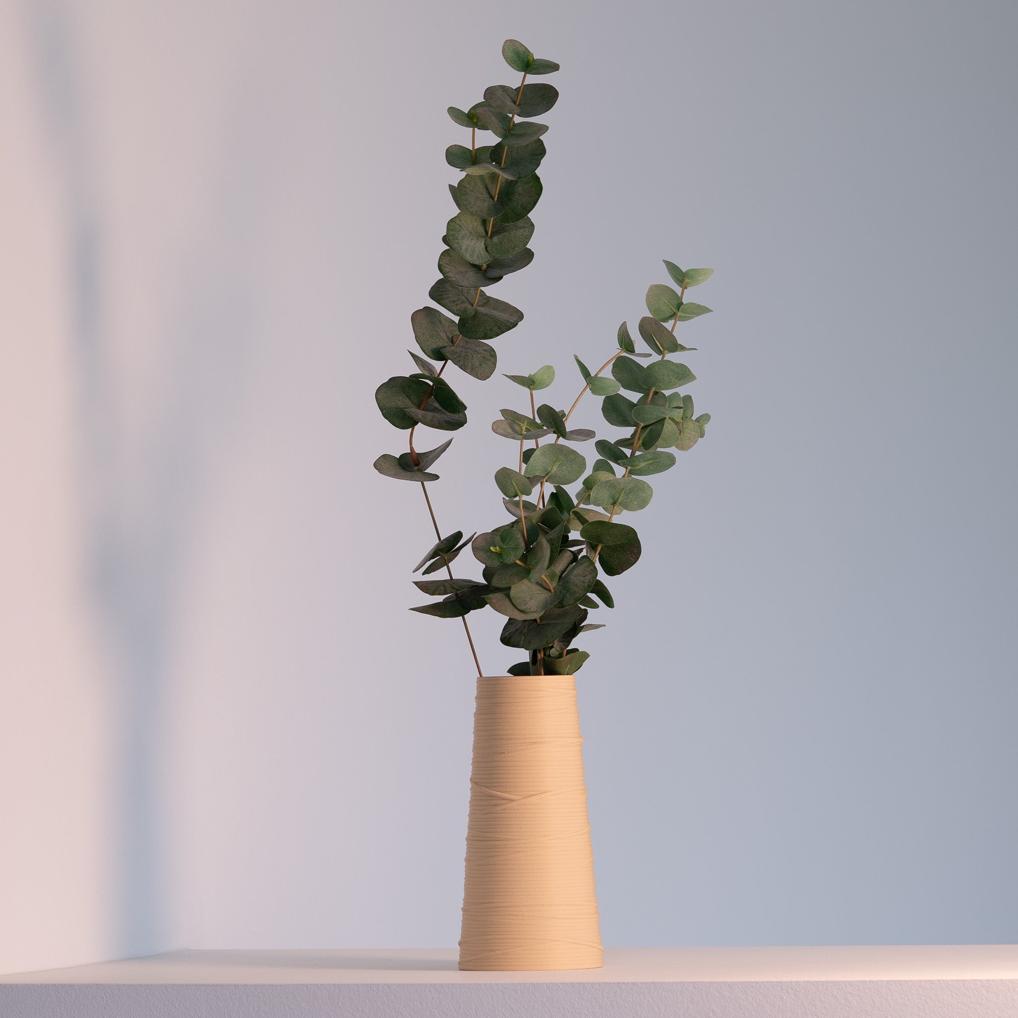 Vase textured with green leaves on a light background