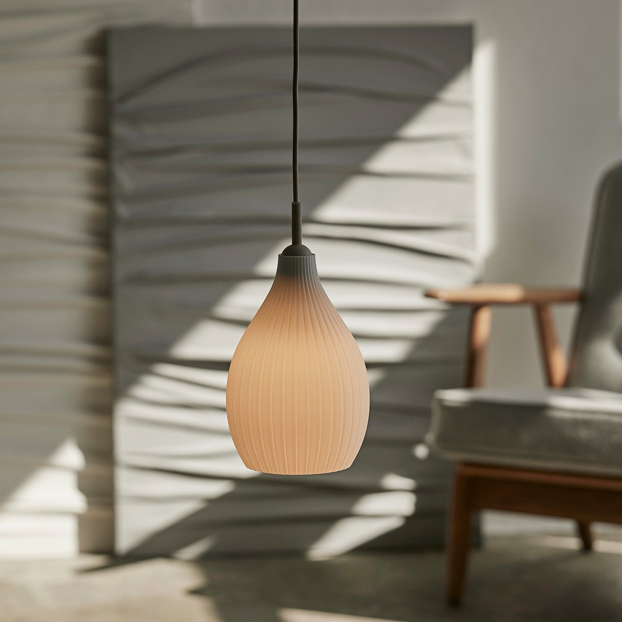 Pendant light hanging in a room with a wall and chair.