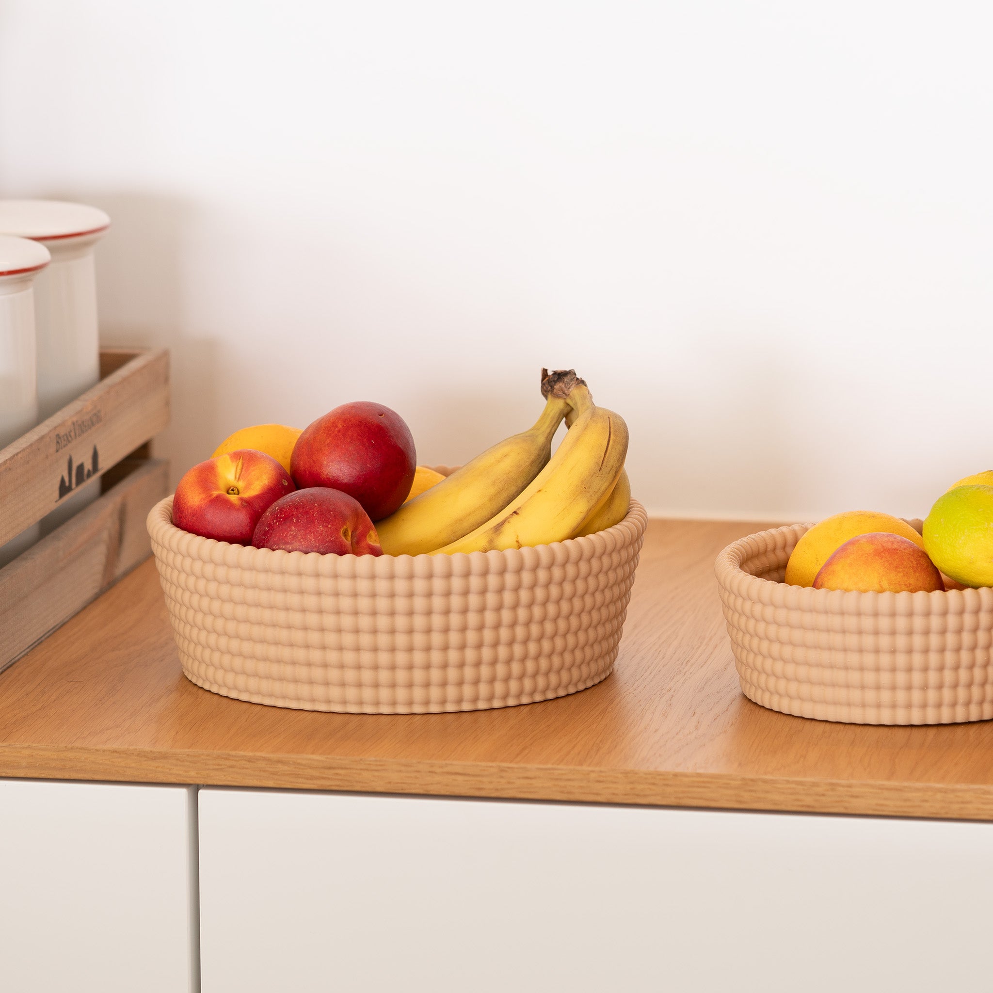 Fruit bowls with woven texture apples and bananas on a wooden surface