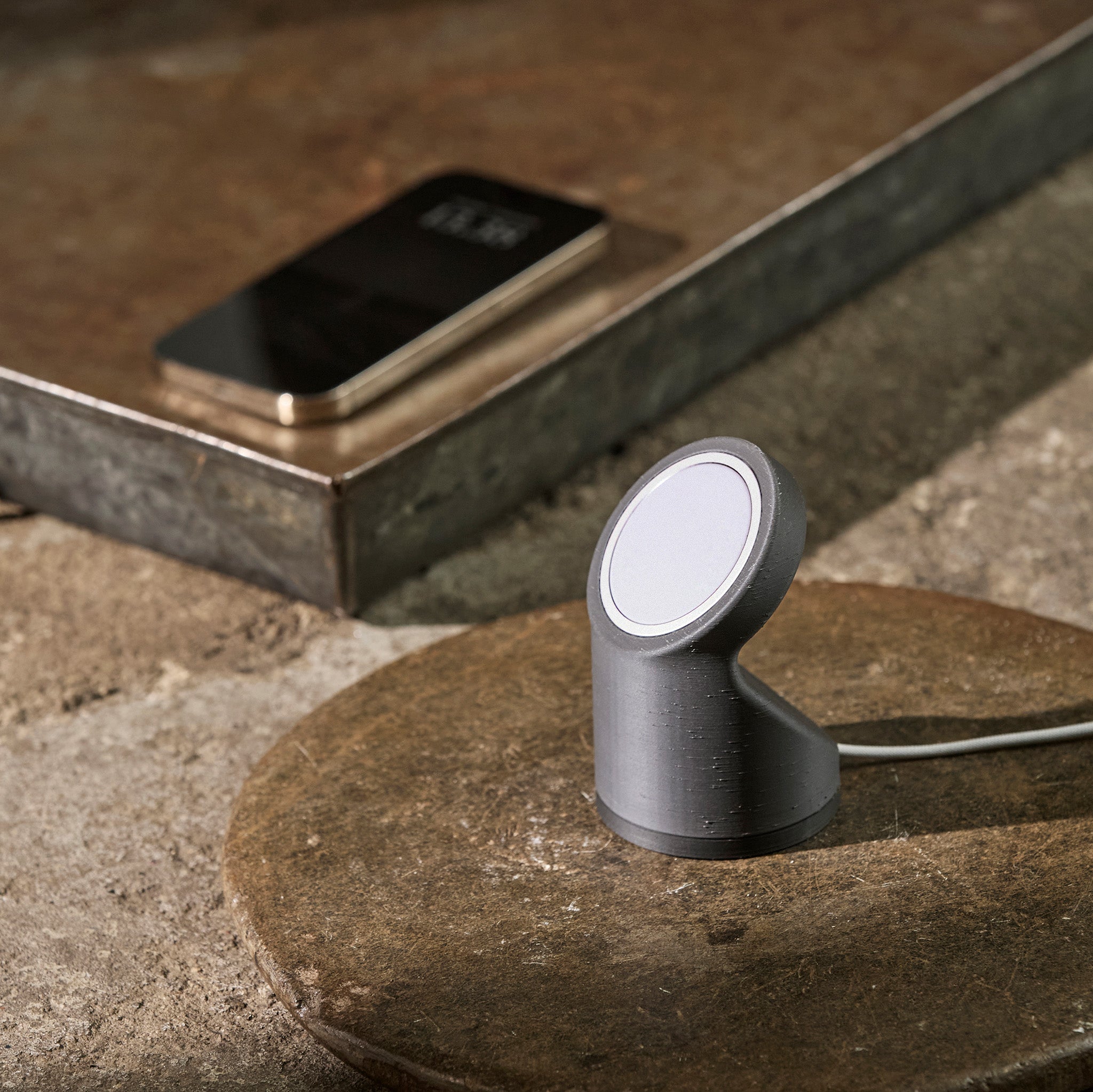Smartphone and wireless charger stand on a stone surface