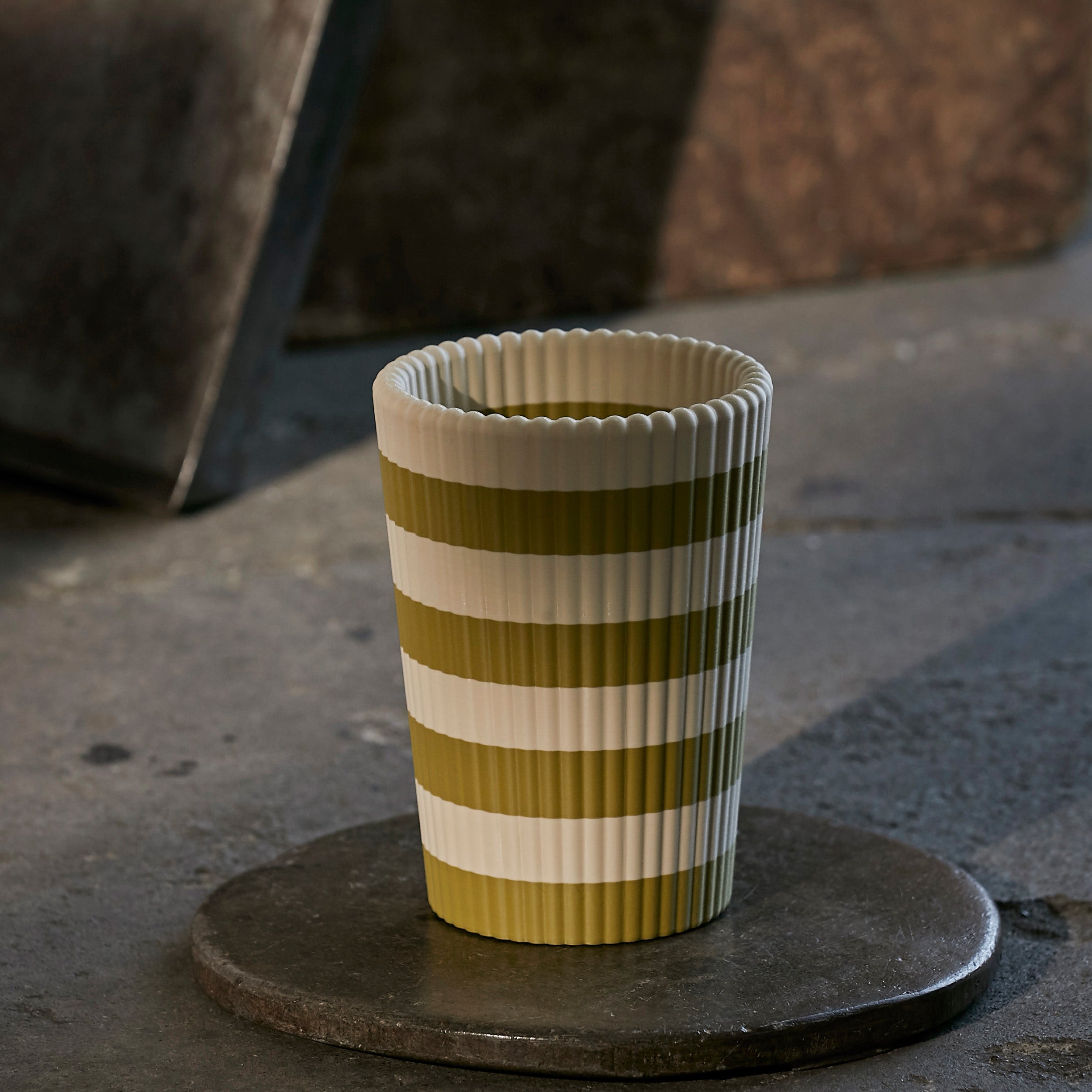Striped wine cooler on a dark surface with blurred background