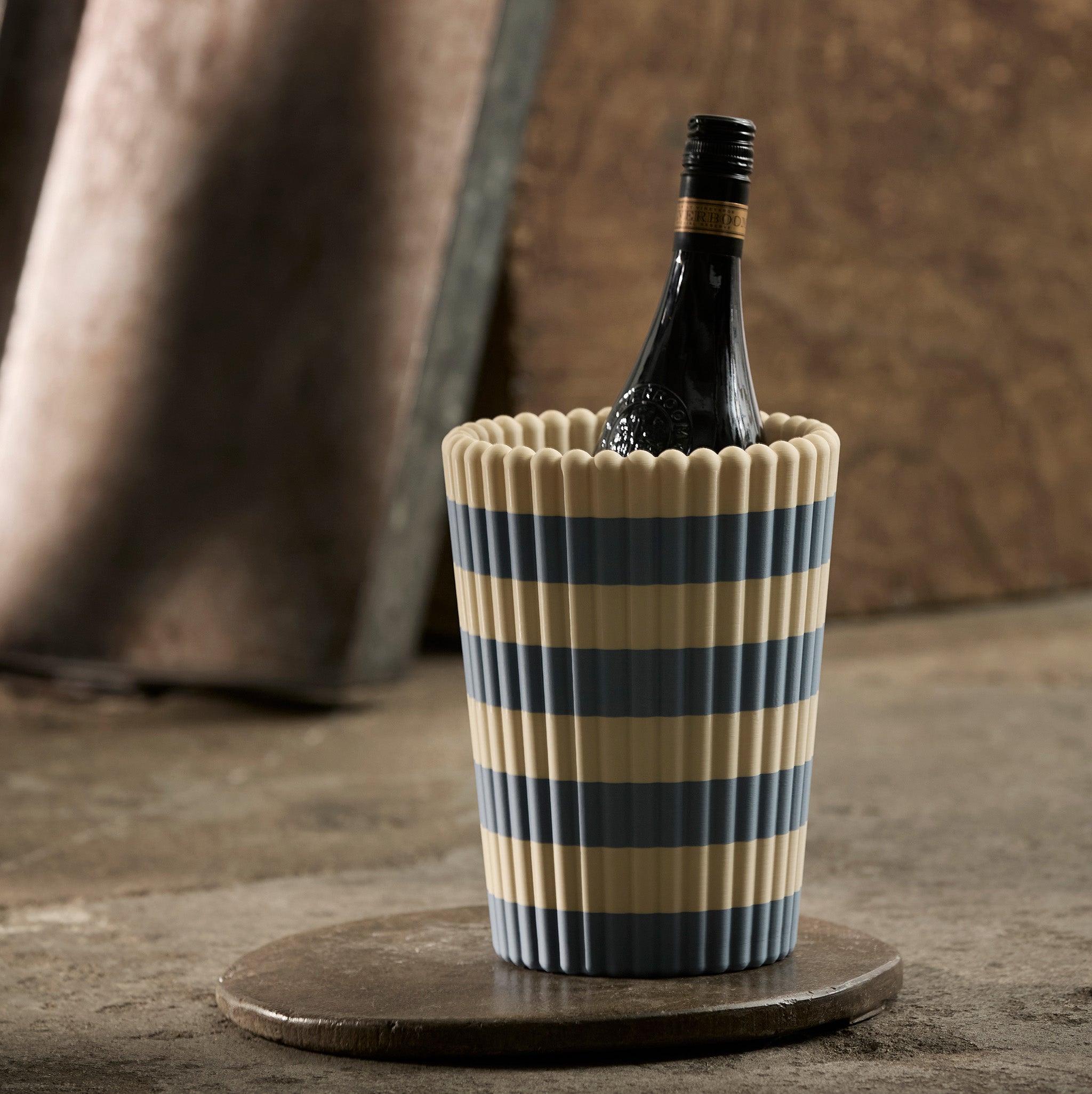 Wine bottle in a striped cooler on a wooden surface with a rustic background