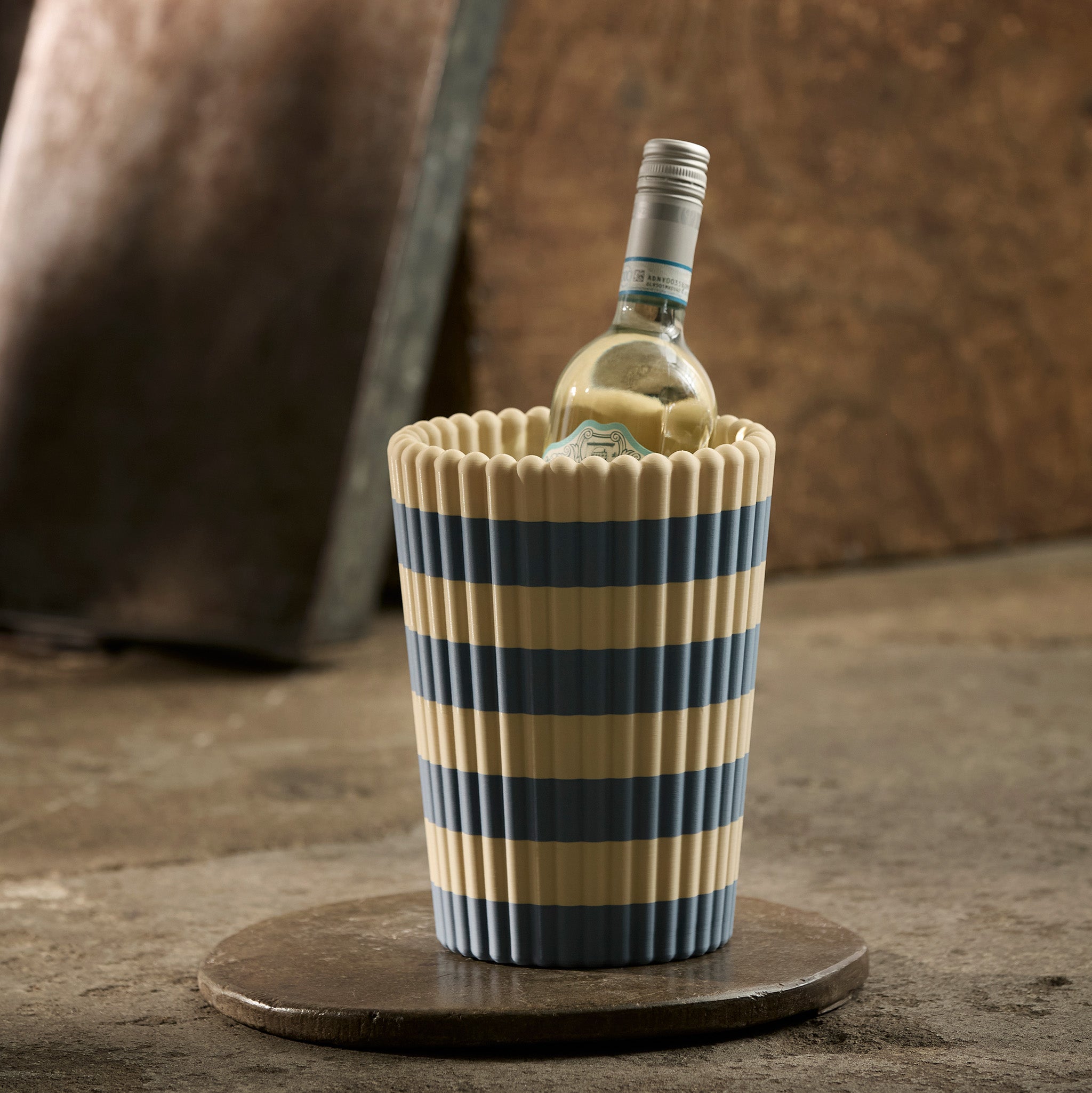 Striped wine cooler with a bottle of white wine on a wooden surface.