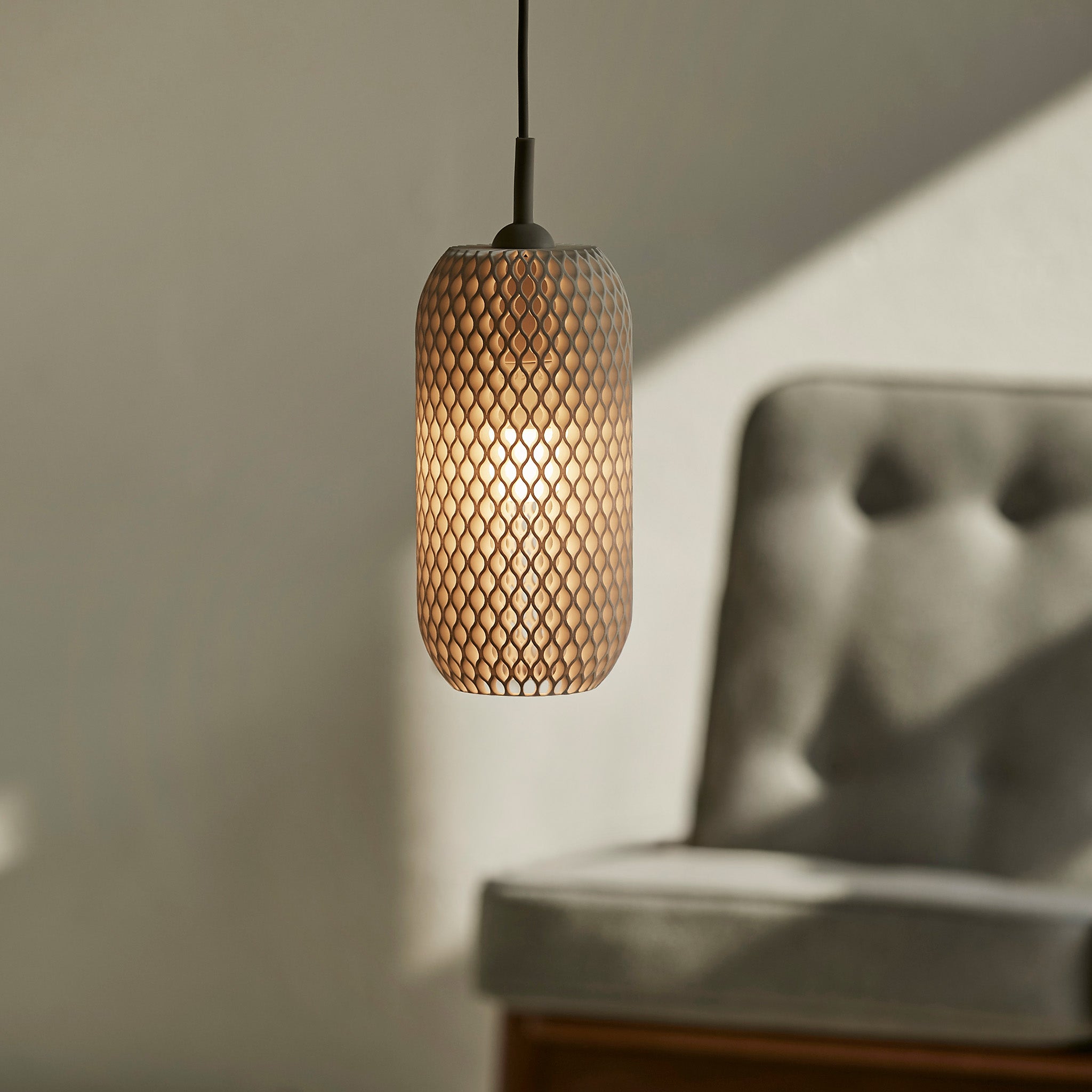 Woven pendant light hanging in a room with a blurred sofa in the background
