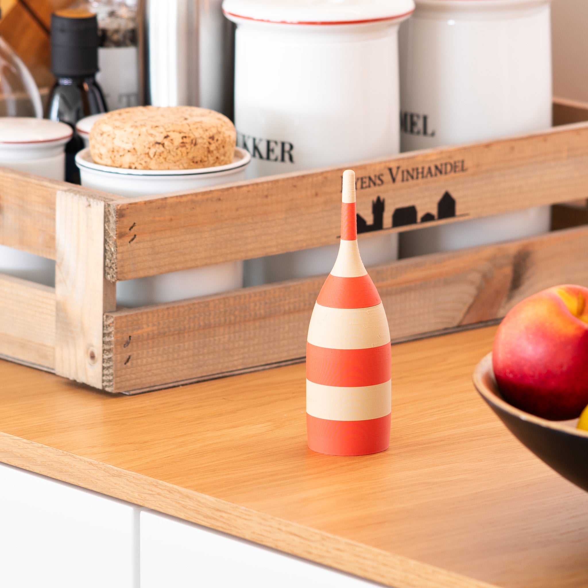 Red and white striped toothpick dispensers on a wooden shelf with a bowl of fruit and a wooden crate in the background.