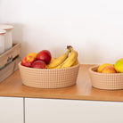 Fruit bowls with woven texture apples and bananas on a wooden surface